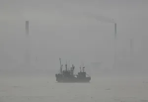 Korea Prints: A North Korean boat is seen on the Yalu River on a hazy day near the North Korean town of