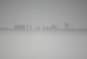 Korea Prints: North Koreans are seen on the banks of the swelling Yalu River on a hazy day near
