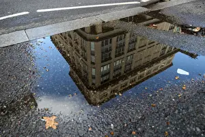 The offices of British life insurer Prudential are reflected in a puddle in London