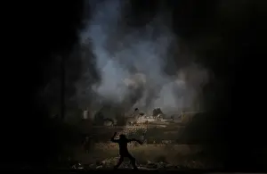 Prints of A Palestinian demonstrator uses a sling to hurl stones at Israeli troops during a protest ahead of the 70th anniversary of Nakba, near the Jewish settlement of Beit El, near Ramallah Israel Prints: Palestinian demonstrator uses a sling to hurl stones at Israeli troops during a protest