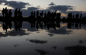 Palestinian demonstrators are reflected in rain water after attending a protest