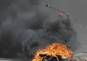 Palestinian Prints: A Palestinian protester uses a sling to hurl stones towards Israeli troops during clashes