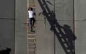 Religion Prints: Palestinian uses a ladder to climb over a section of the controversial Israeli barrier