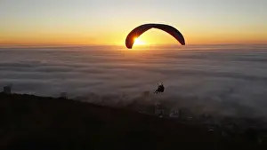 Paragliders take in the last of the days light as a seasonal fog engulfs Cape Town