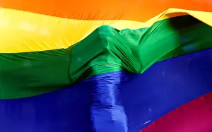 A participant stands behind a rainbow flag during a vigil in memory of the victims