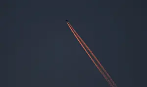 A passenger plane leaves behind contrails as it flies in the skies over London Luton