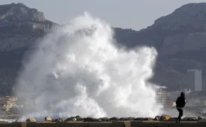 France Prints: A passer-by walks as a high wave hits the waterfront in Marseille