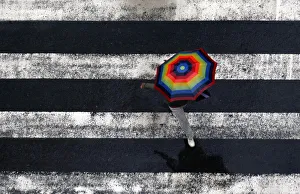 A pedestrian holding an umbrella walks across a crosswalk in Chengdu A pedestrian holding an umbrella walks across a crosswalk in Chengdu