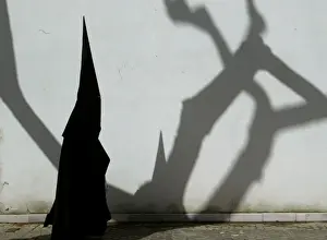 A PENITENT WALKS TO CHURCH FOR A HOLY WEEK PROCESSION IN SEVILLE