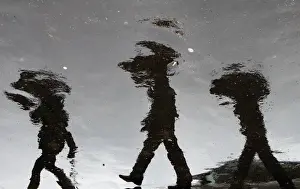 People holding umbrellas are reflected in puddles of rain at the Vatican Radio