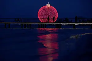 People are seen on a pier in front of a giant illuminated Christmas ball in Larnaca