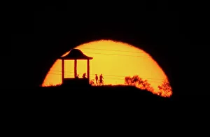 People are silhouetted against the setting sun at El Mirador de la Alemana in Malaga