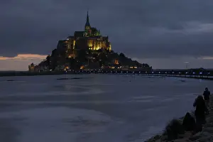 People sit on an embankment as the incoming tide surrounds the Mont Saint-Michel 11th