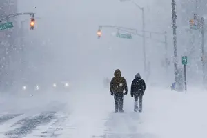 People struggle against wind and snow during Storm Grayson at the Jersey shore in Long