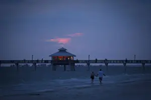 People walk along beach at twilight during the Labour Day long weekend in Ft Myers Beach