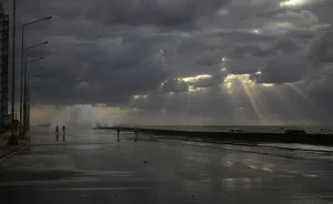 Cuba Prints: People walk as waves crash on the El Malecon seafront boulevard