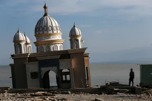 Indonesia Prints: A police officer stands next to the remains of a mosque destroyed by the earthquake