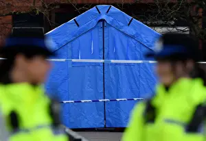 : Police officers stand guard in front of a forensics tent in a cordoned off area in