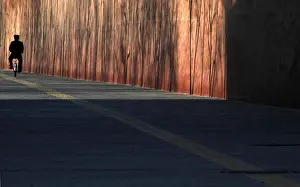 A policeman rides a bicycle beside the wall surrounding the Forbidden City in central
