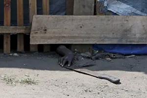 A protester, hiding from police, tries to retrieve a machete during a protest against