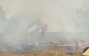 Prints of A protester holding a Palestinian flag runs for cover from tear gas fired by Israeli troops during clashes at a protest ahead of Nakba day, in the West Bank village of Bilin near Ramallah May 13 Israel Prints: Protester holding a Palestinian flag runs for cover from tear gas fired by Israeli troops
