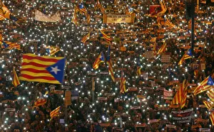 Protesters hold the lights of their mobile phones as they wave Estelada flags during a