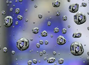 Rain drops on a car window reflects a man walking past a stock index board in Tokyo