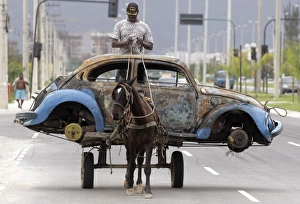 Prints of A Brazilian man transports on his horse-drawn cart the remains of a Volkswagen Beetle that caught fire and was abandoned by its owner the day before in Rio de Janeiro Brazil Prints: Rp6Drnatfvac