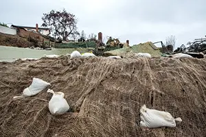 Prints of Sandbags and webbing are seen on a small hill in front of a house burned to the ground in the Thomas Fire during a winter rain storm in Ventura, California, U.S. January 9, 2018 USA Prints: Sandbags and webbing are seen on a small hill in front of a house burned to the ground in