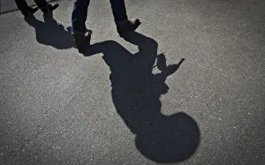 Abstract Prints: The shadow of a gunfighter is cast on the asphalt as competitors practice prior to