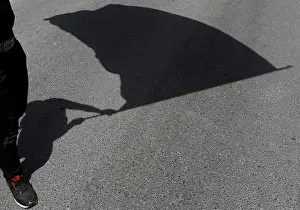 The shadow of a protester holding a flag is seen on the road during a May Day rally