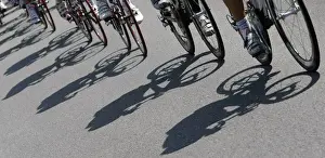 Shadows are cast on the road as the pack of riders cycles during the twelfth stage