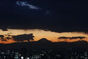 The silhouette of Japans highest mountain Mount Fuji is seen beyond buildings in Tokyo