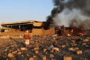 Security Prints: Smoke rises as people inspect damage at the site of air strikes in the city of Saada