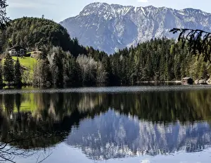 Snow covered mountains are reflected in Piburger lake on a sunny spring day in