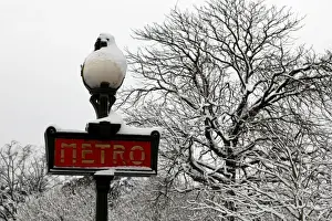 France Prints: Snow covers a Metro sign and tree branches as winter conditions with snow