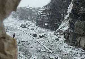 Crisis Prints: Snow falls over damaged buildings at Jouret al Shayah area in Homs