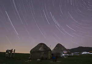 Star trails form over yurts in a long exposure picture on the mountainous Assy plateau