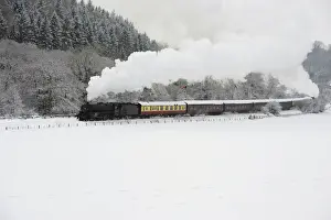 A steam train is seen running through a snow covered valley between Pickering