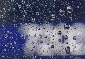 Market Prints: Stock prices displayed on an electronic board are reflected on raindrops on the window of