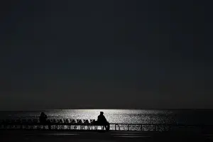 France Prints: Sunlight reflects on the waters surface as people sit on chairs on a warm