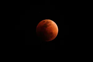 Lunar Prints: A super blood blue moon is seen during an eclipse, behind an office building in Hong