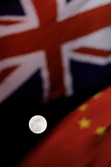 Lunar Prints: The super blue moon is seen between British and Chinese flags raised at Tiananmen square