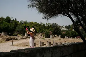 A tourist takes pictures with her phone as she visits the Roman Agora archaeological site