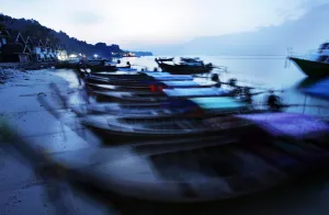 Thailand Prints: Traditional Thai fishing boats are swayed by small waves as they are anchored on a