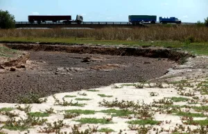 : Trucks pass by a dried-up creek bed in a drought-affected area near Chivilcoy