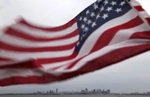 Prints of A U.S. flag flutters over top of the skyline of New York (R) and Jersey City (L), as seen from Bayonne, New Jersey, August 6, 2011 USA Prints: A U. S. flag flutters over top of the skyline of New York and Jersey City