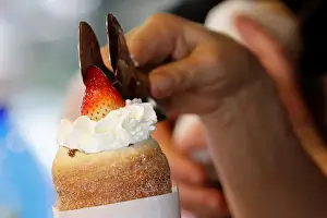 A vendor prepares a traditional Trdelnik sweet pastry in Prague