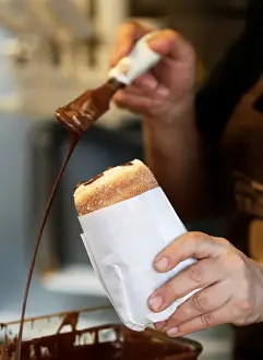 Confectionery Prints: A vendor prepares a traditional Trdelnik sweet pastry in Prague