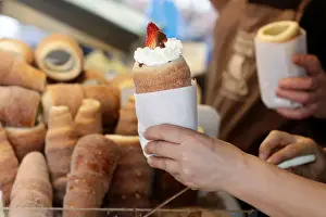 Confectionery Prints: A vendor prepares a traditional Trdelnik sweet pastry in Prague